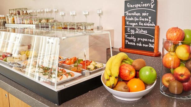 A breakfast buffet with various food items and a sign indicating fresh egg dishes.