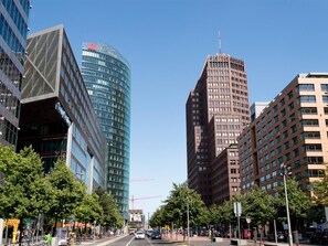 A city street lined with modern buildings, including a curved glass skyscraper and a tall brick building. - Flottwell Berlin Hotel & Residenz am Park (Berlin)