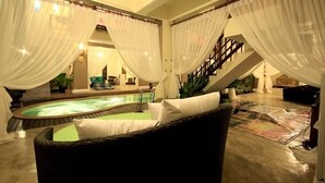 A spa area with a hot tub, a wicker chair, and a staircase. - Devara Pool Villa (Pattaya)