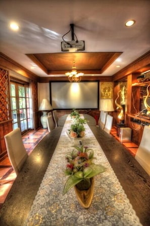 A conference room with a long table, chairs, a chandelier, and decorative elements like plants and sculptures.