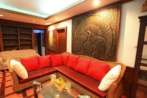 A living room with a sofa, a glass coffee table, and a decorative wall panel.