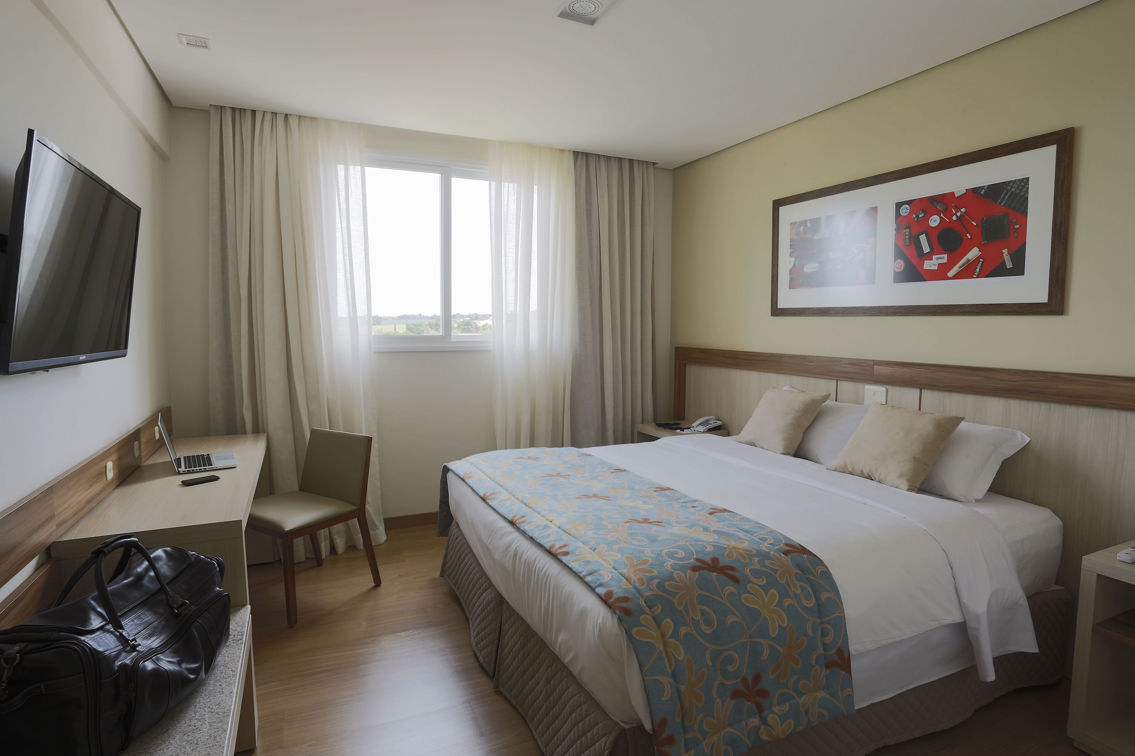 Ein Hotelzimmer mit Bett, Schreibtisch, Stuhl und Fernseher.