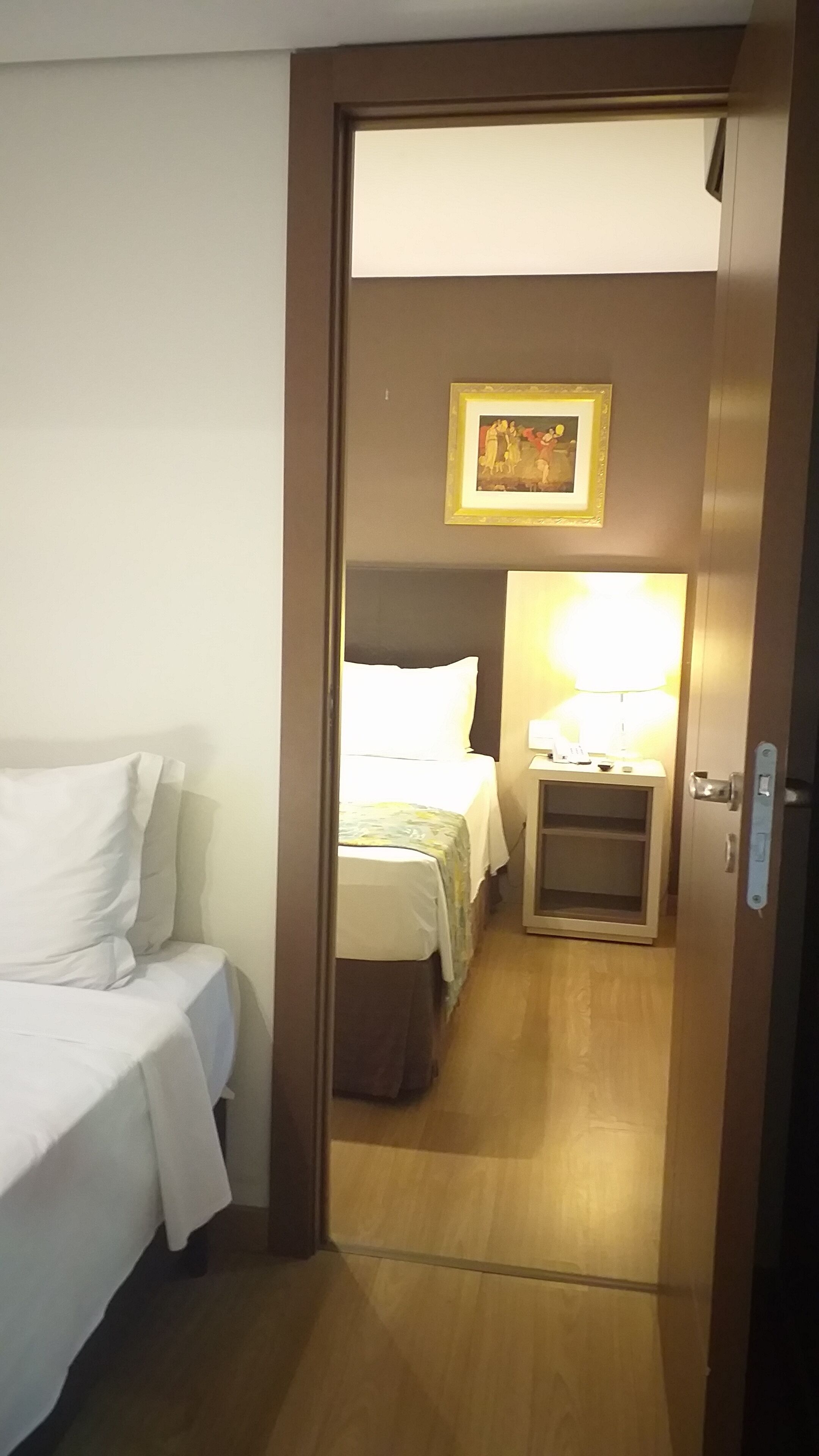 Une chambre d’hôtel avec un lit, une table de chevet avec une lampe et un tableau encadré au mur.