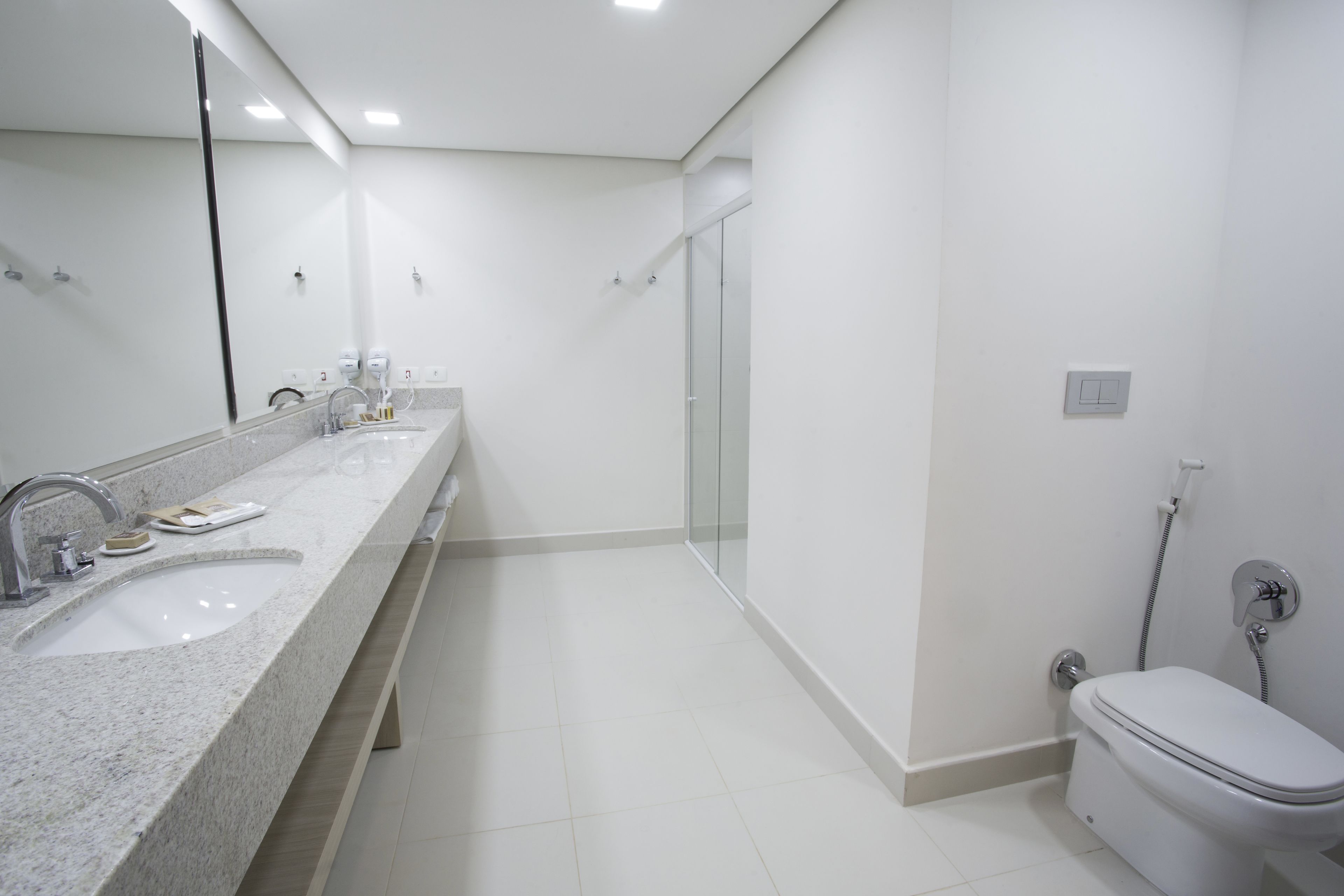 A modern bathroom with a large mirror, a sink, a toilet, and a glass shower enclosure.