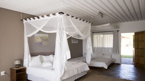A bedroom with a canopy bed, a bedside table with a lamp, and a view of the outside. - Dornhügel Guestfarm (Grootfontein)
