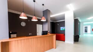 A reception area with a wooden desk, a clock, and a red couch. - Itajai Express (Itajai)