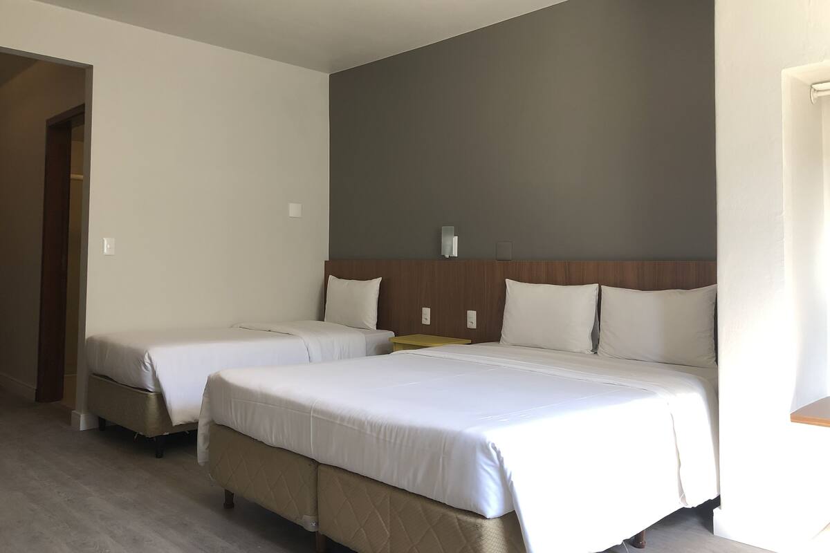 A hotel room with two beds, a wooden headboard, and a small table.