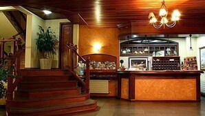 A hotel lobby with a wooden staircase, a reception desk, and a large plant. - Pousada do Bosque (Canela)