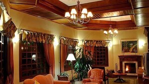 A cozy living room with a fireplace, a sofa, and a television. - Pousada do Bosque (Canela)