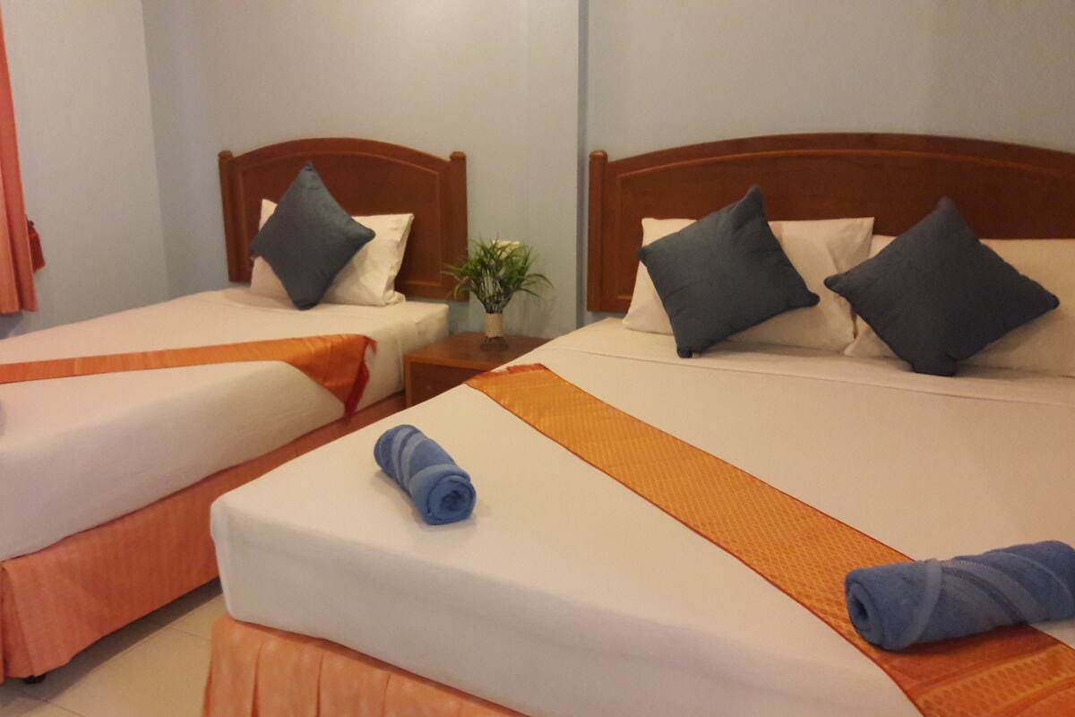 Two single beds with wooden headboards, white bedding, and blue towels.
