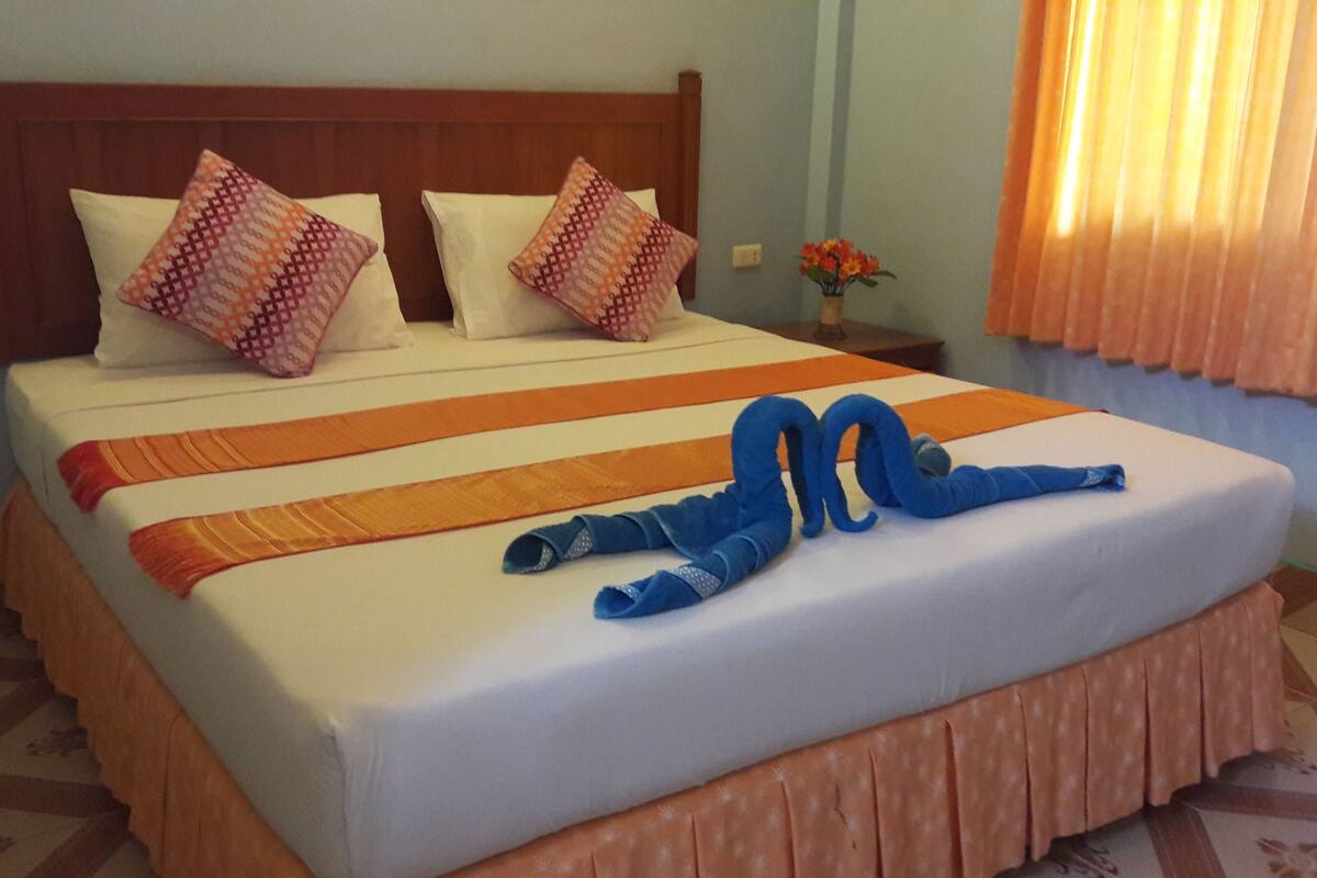 A neatly made bed with a patterned bedspread, pillows, and a blue decorative item.