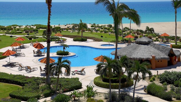 A resort with a large pool, palm trees, and a beach view. - Casa del Mar Condos (San José del Cabo)