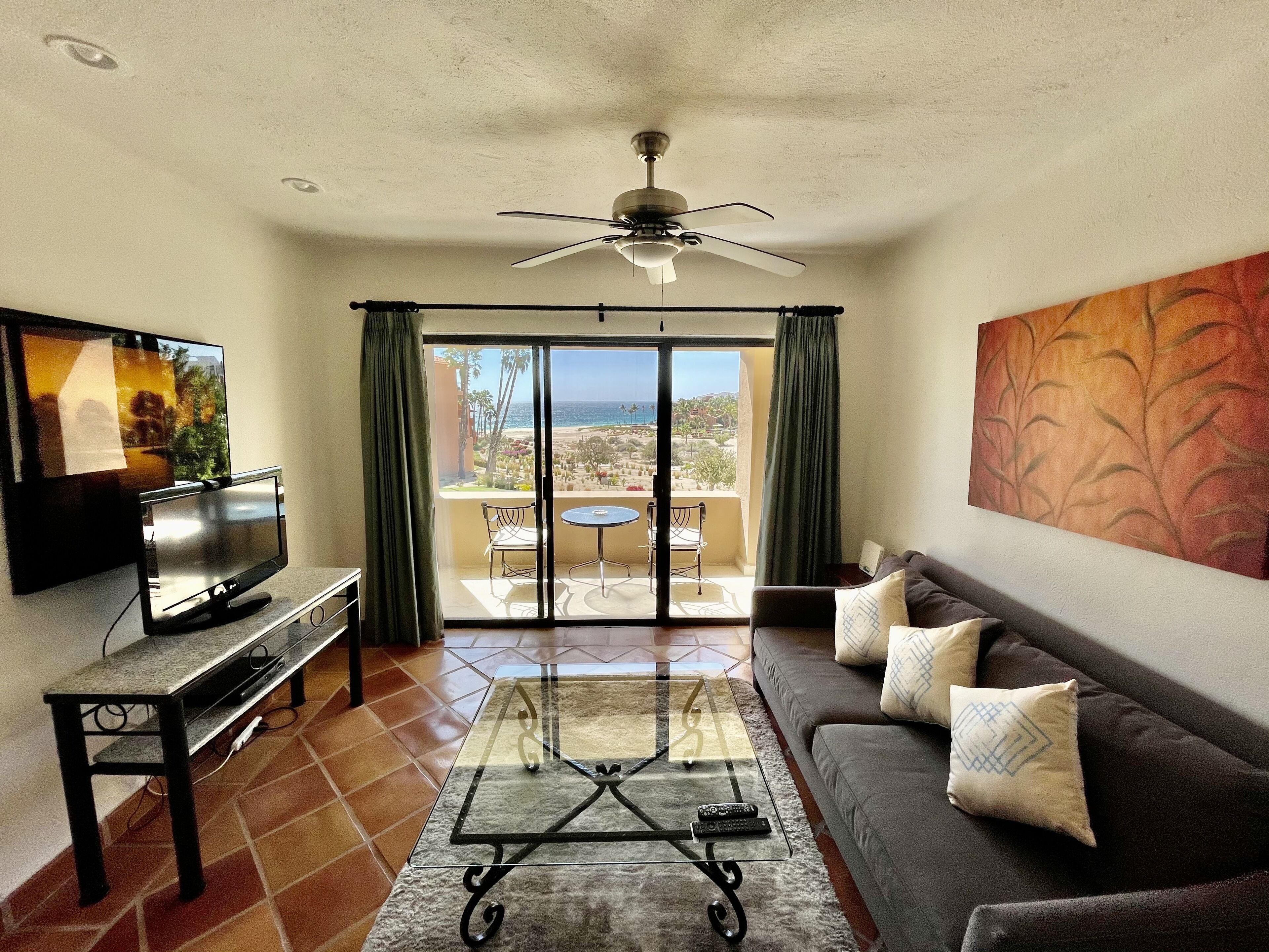 A living room with a TV, sofa, coffee table, and a balcony with a view.
