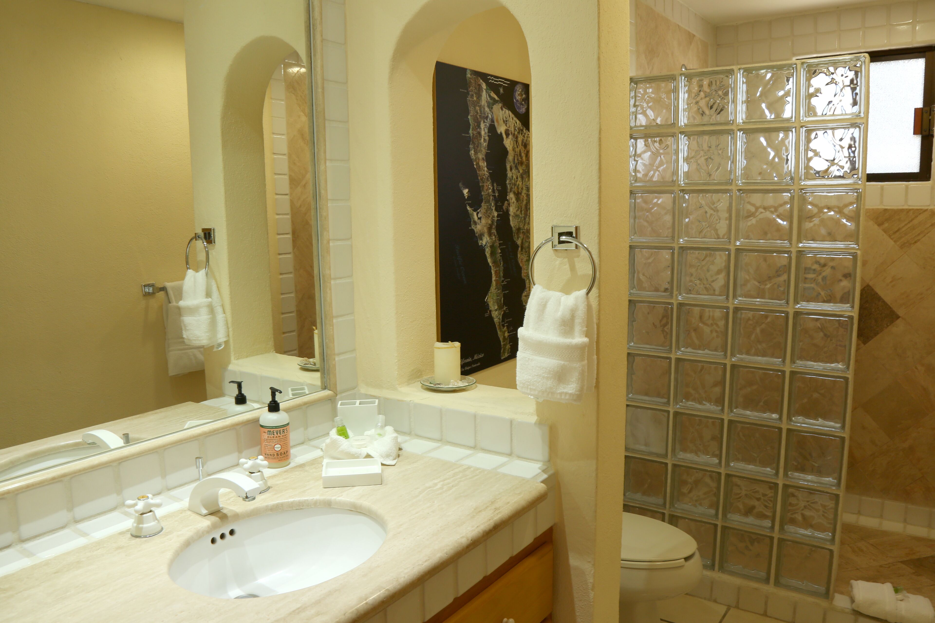 A bathroom with a sink, mirror, towel rack, and shower area.