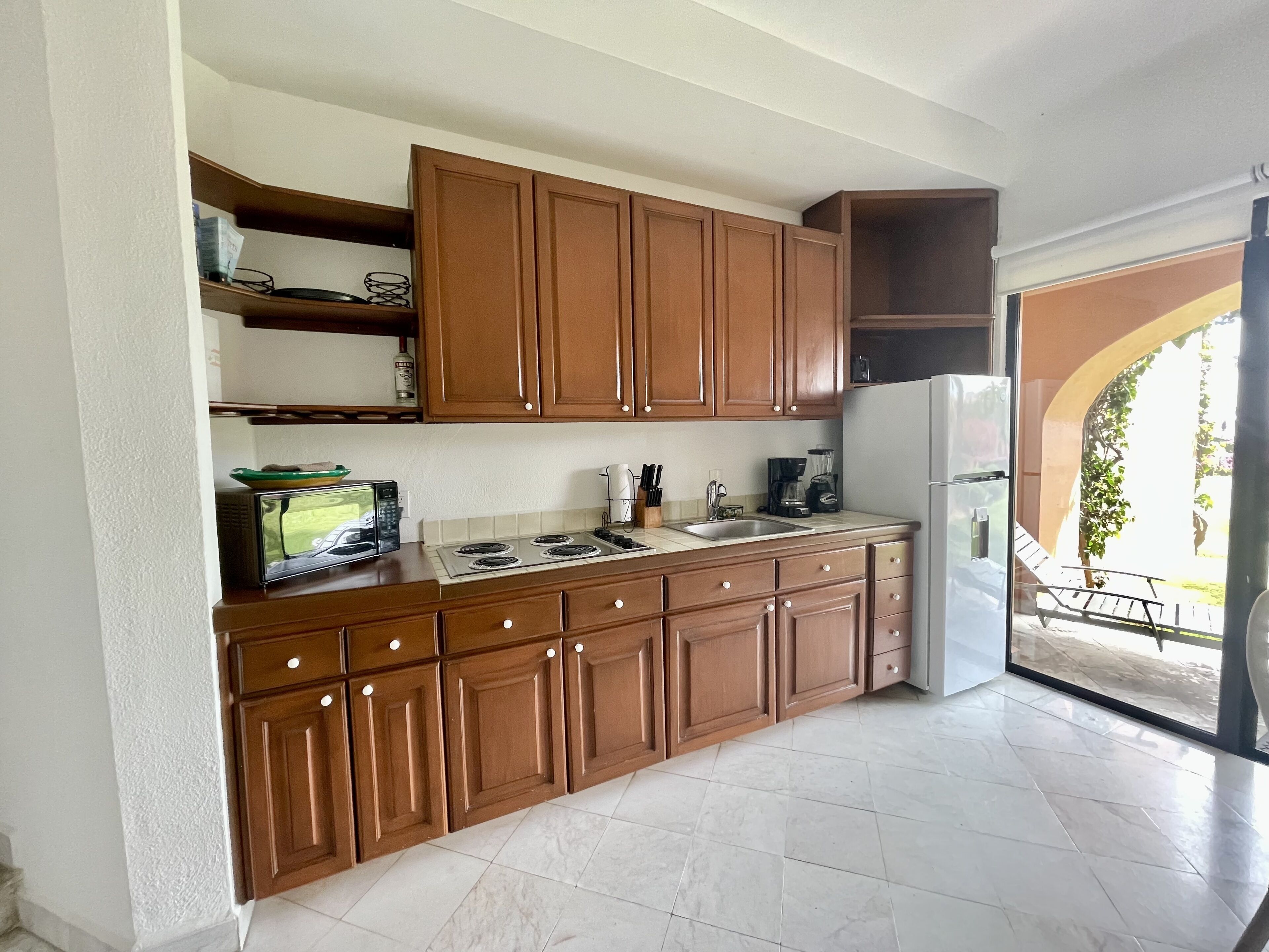 Une cuisine avec des meubles de rangement en bois, une cuisinière, un évier et un réfrigérateur.