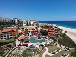 A resort with multiple buildings, a central pool area, and a beach.