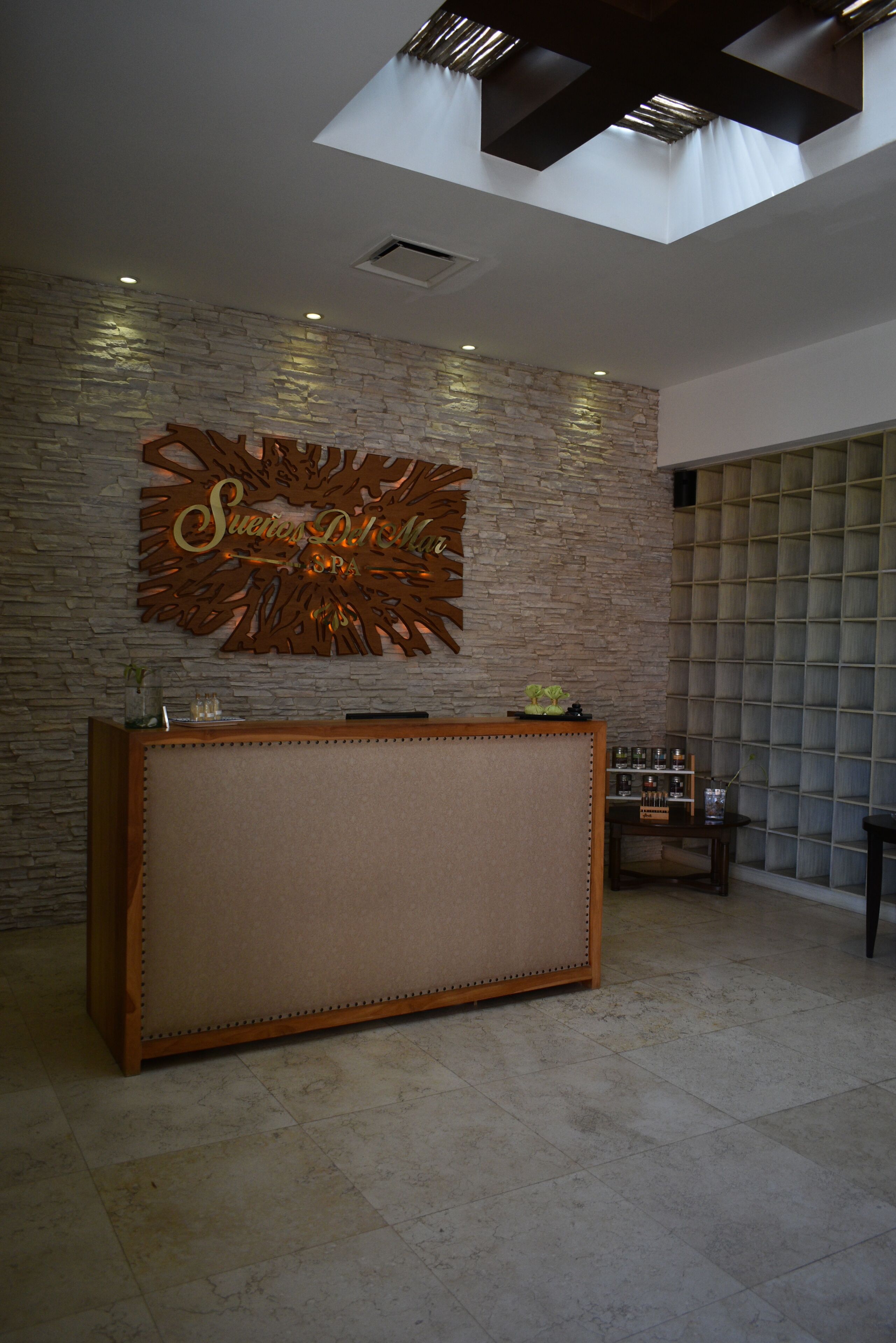 Un área de recepción con una pared de piedra, un mostrador de madera y un letrero decorativo.