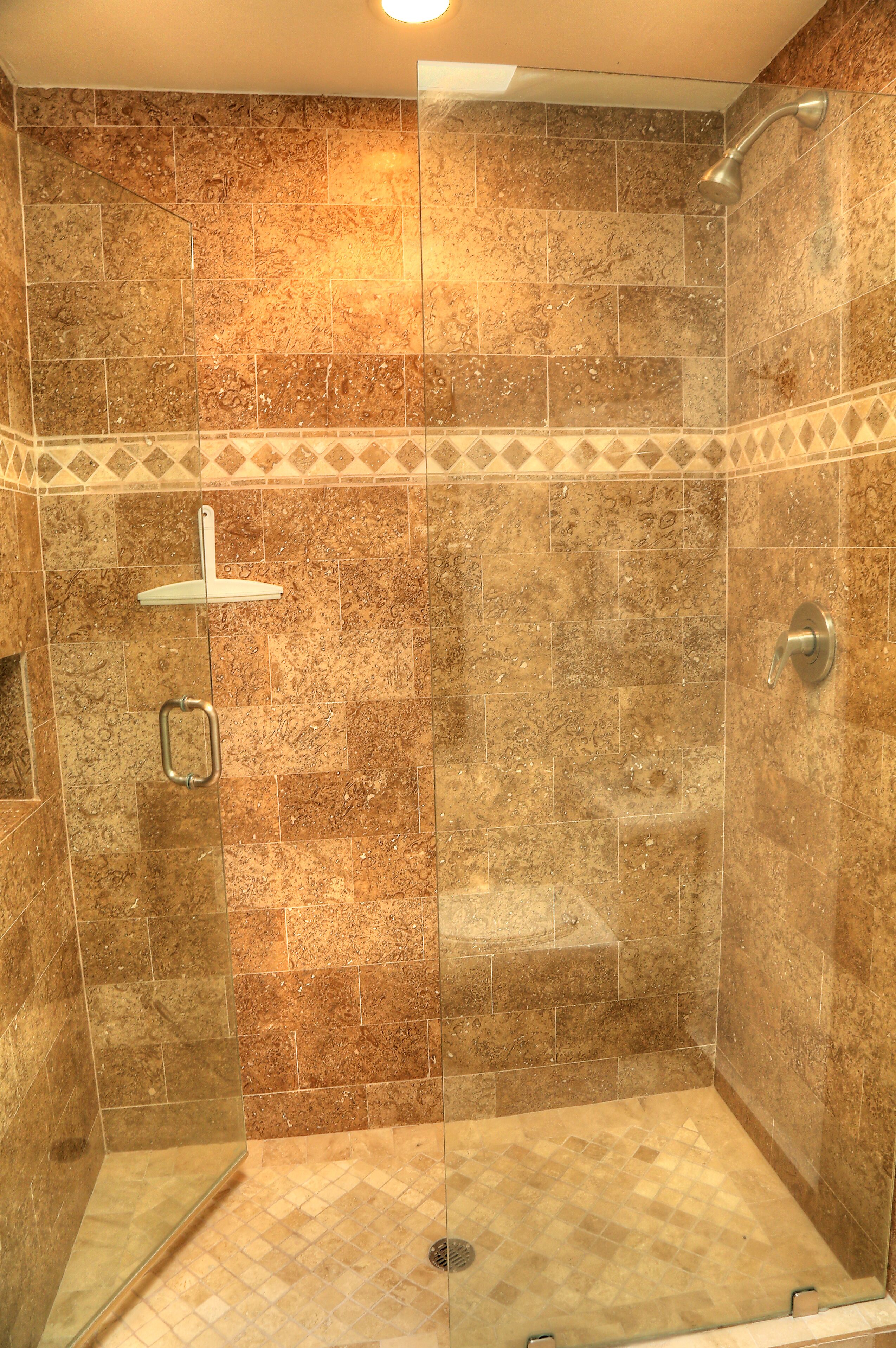 A walk-in shower with a glass door, tiled walls, and a showerhead.