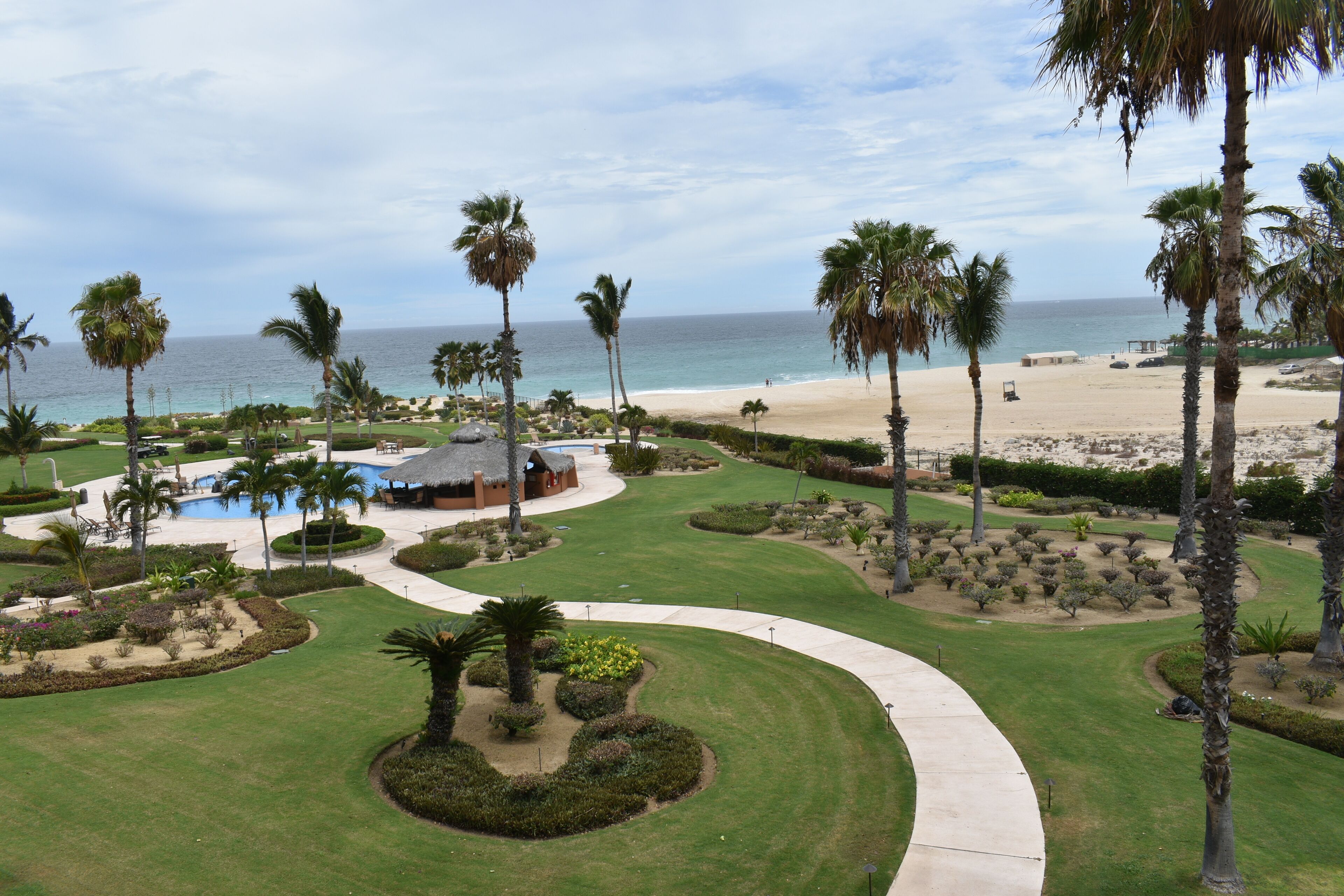 A resort with a pool, palm trees, and a beach view.