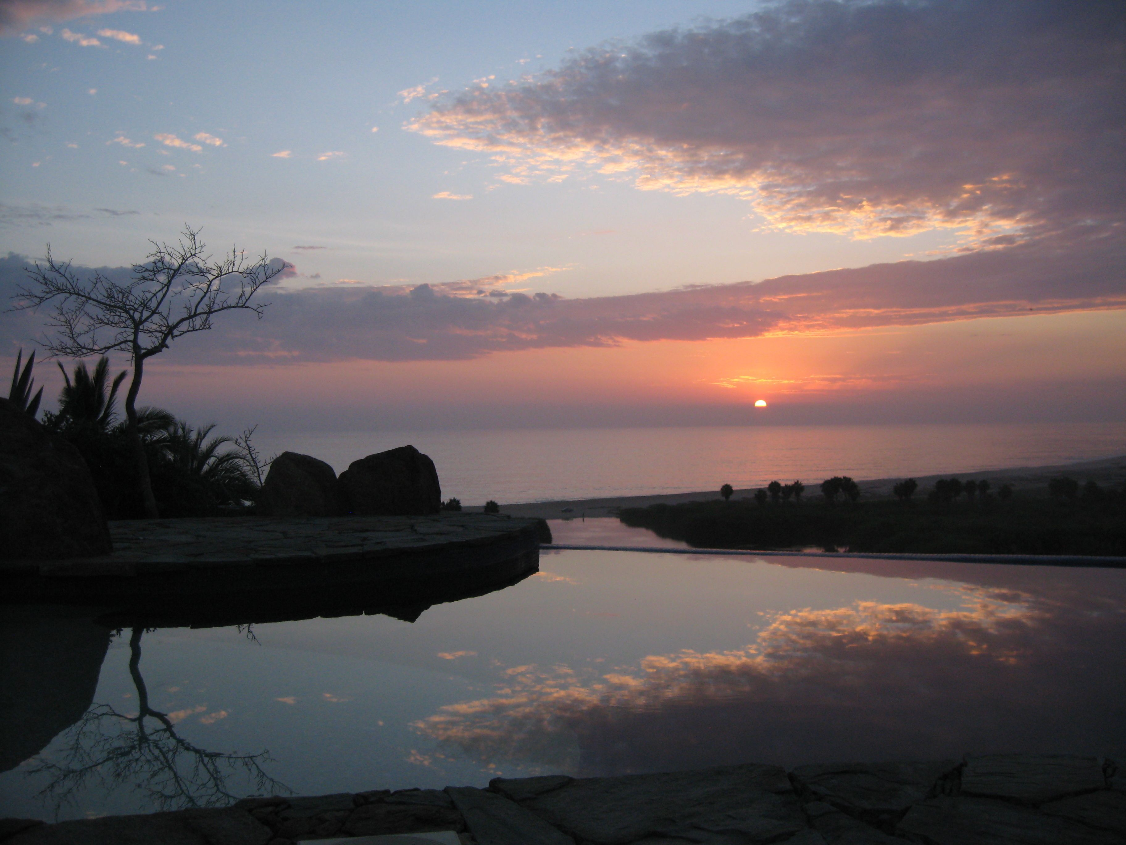 Un atardecer sobre un río tranquilo con afloramientos rocosos y vegetación escasa.