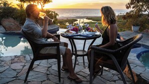 Una pareja cenando en una mesa con vistas al océano y una piscina.