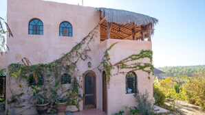 Un edificio de enlucido con ventanas de arco, tejado de paja y plantas en macetas.