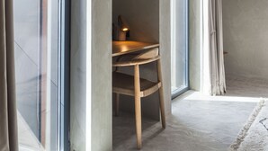 A room with a wooden chair, a desk, and a lamp.