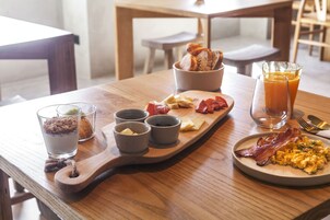 Una mesa de desayuno con huevos revueltos, tocino, tostadas y un vaso de jugo de naranja.