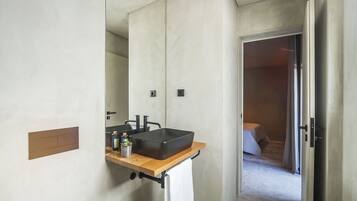 A modern bathroom with a large mirror, a black sink, and a wooden countertop.