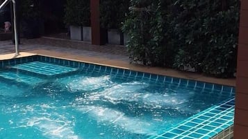 Una piscina al aire libre, sombrillas, sillones reclinables de piscina