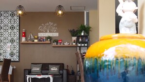 A modern living room with a sofa, decorative wall art, and a variety of potted plants. - Chitra Villa (Pattaya)