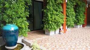 A courtyard with a large blue vase, potted plants, and a tiled floor. - Chitra Villa (Pattaya)