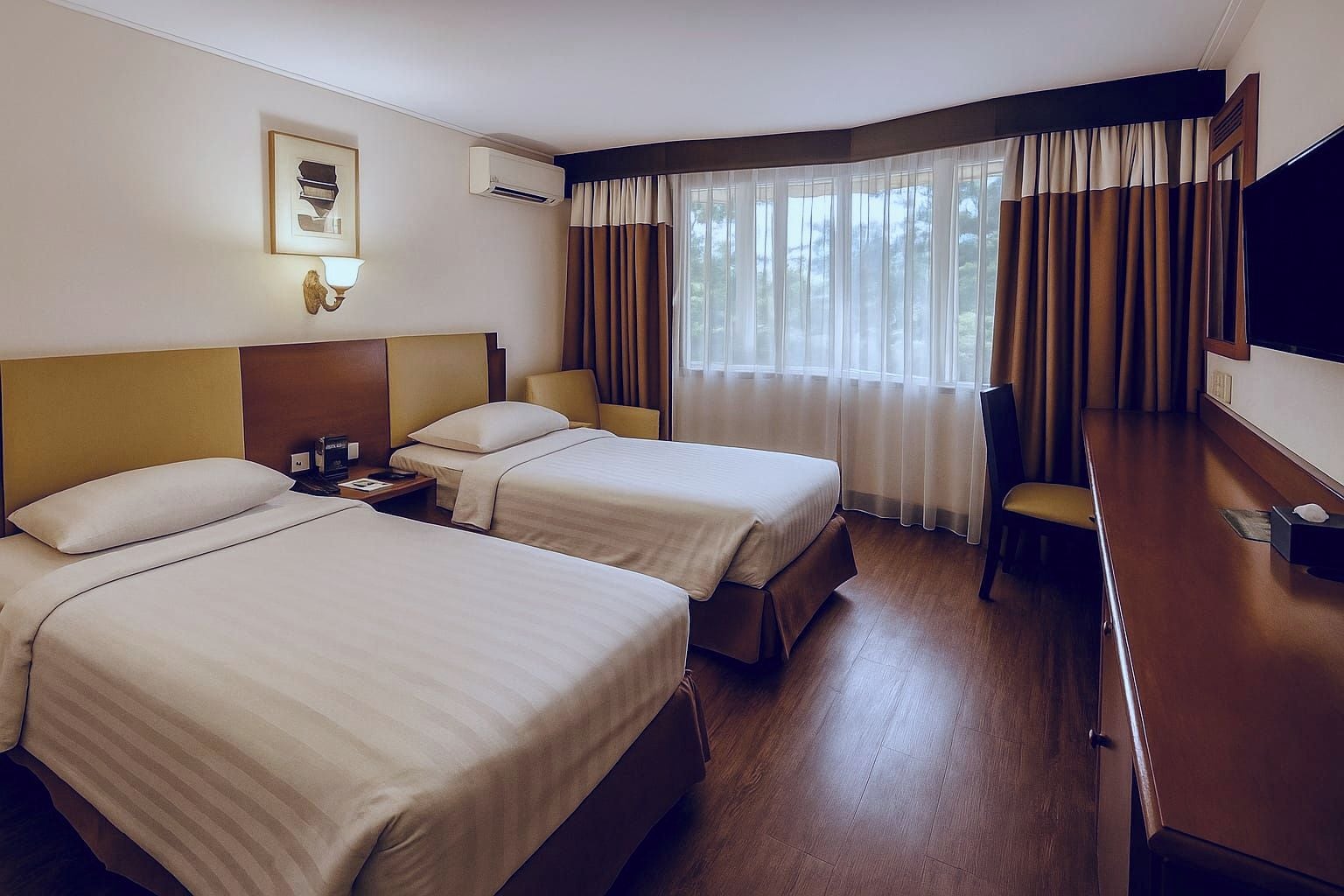 A hotel room with two beds, a desk, a chair, a TV, and a window with curtains.