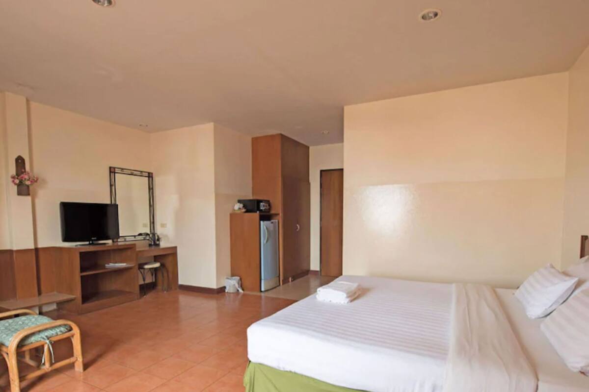 A hotel room with a bed, a desk with a television, a chair, and a wardrobe.