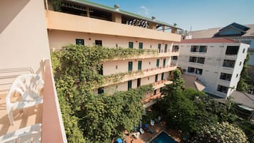 A multi-story hotel with a rooftop terrace, outdoor pool, and lush greenery.