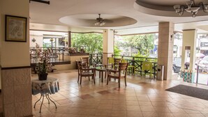 A spacious indoor area with a tiled floor, wooden chairs, a round table, and a ceiling fan. - Opey De Place (Pattaya)