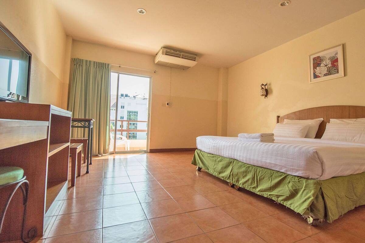 A hotel room with a bed, a desk, a chair, and a large window.