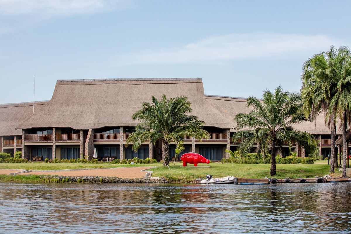 A hotel with a flat roof, multiple balconies, and a pool area with palm trees.
