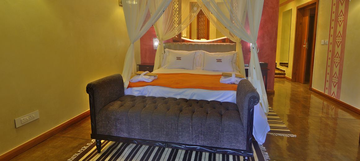 A bedroom with a four-poster bed, a canopy, and a striped rug.
