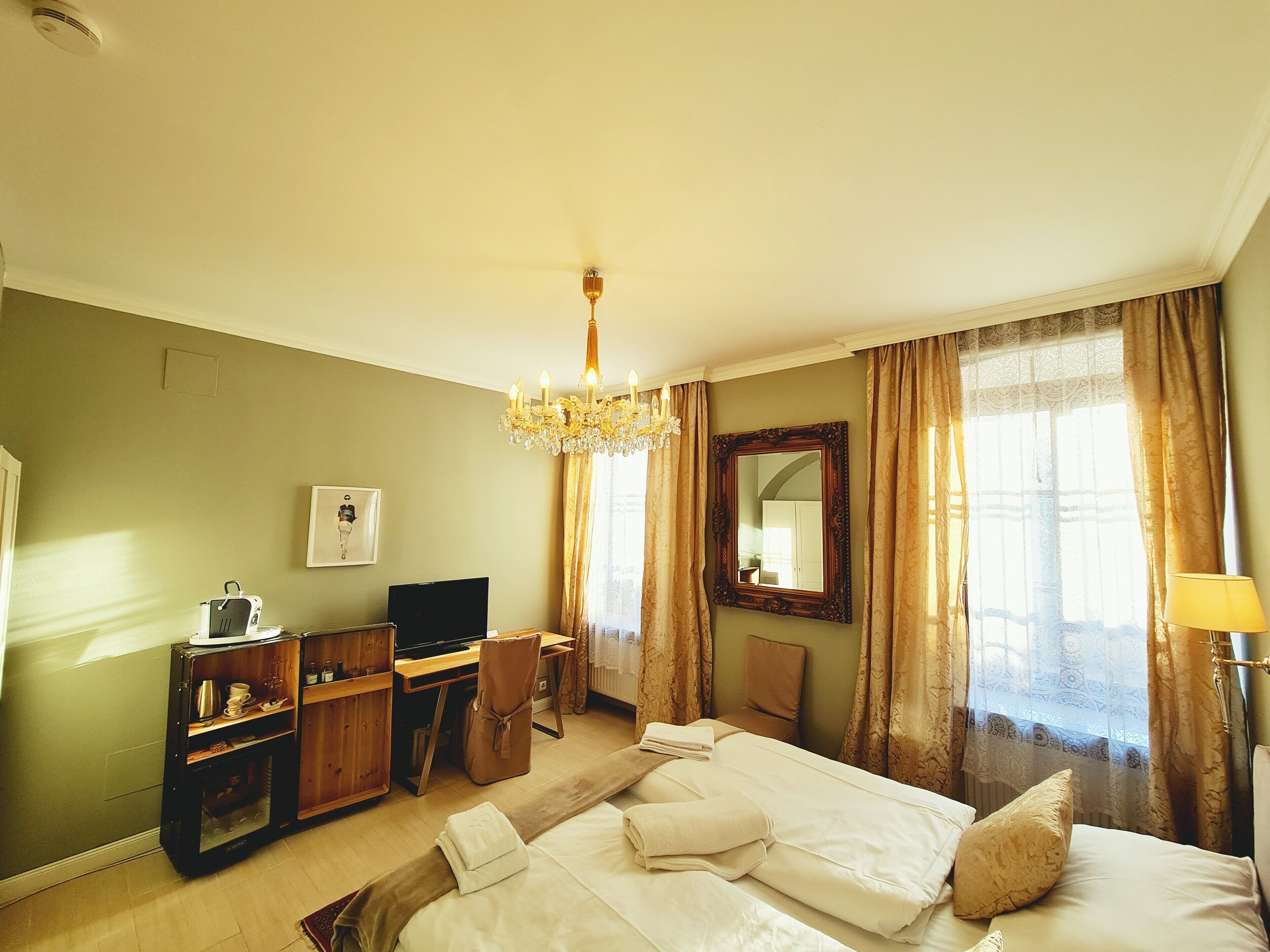 Una habitación de hotel con una cama, un escritorio con una silla, una televisión y un candelabro.