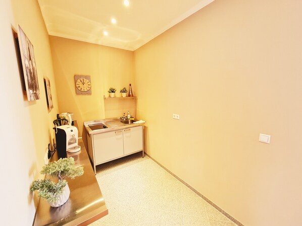 A compact kitchen with a sink, countertop, and cabinets. There is a clock on the wall and a small potted plant on the counter. - Gewerkenschlössl Zeilinger (Knittelfeld)
