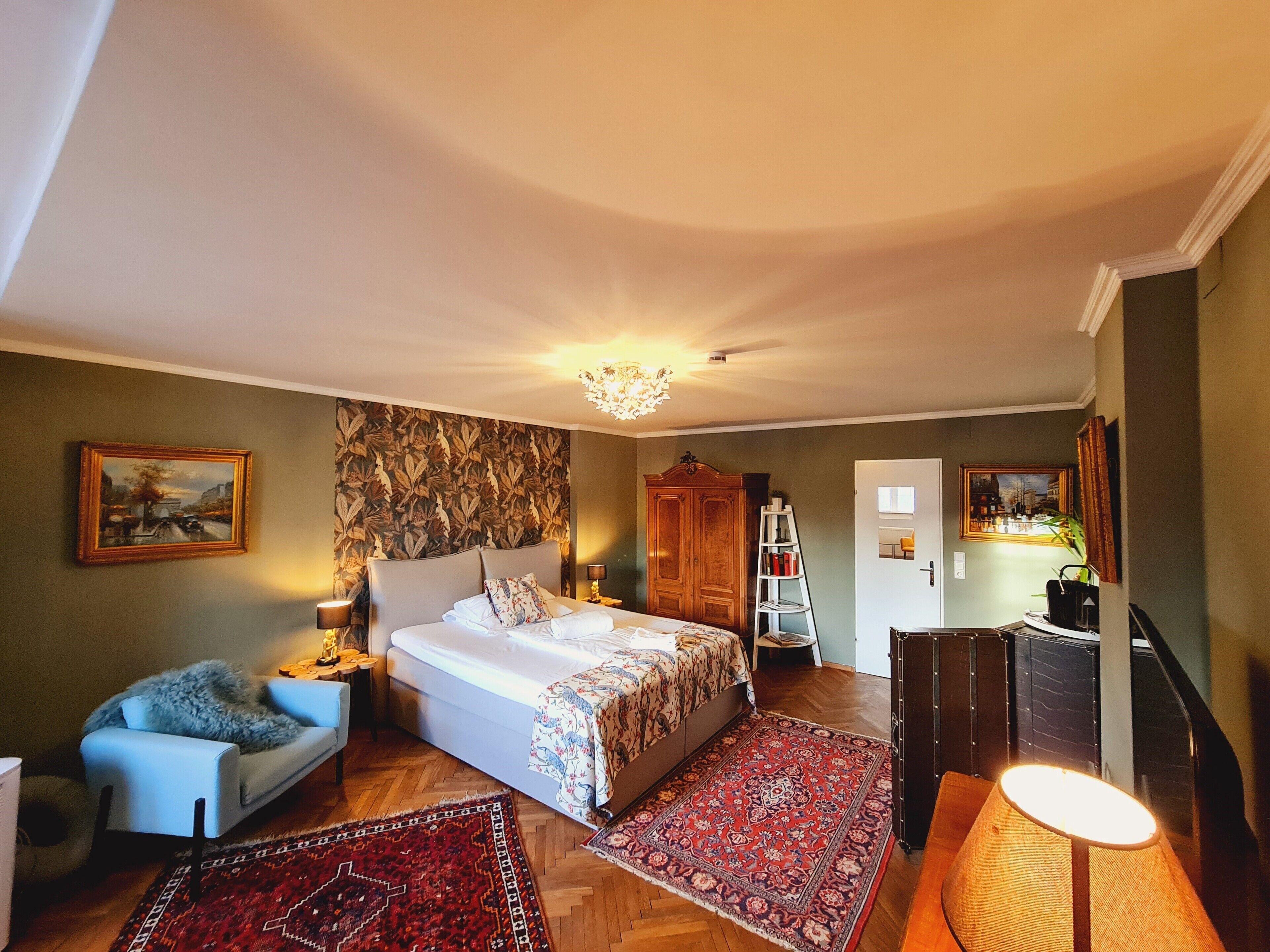 A bedroom with a bed, a chair, a desk, a ladder, and a staircase.