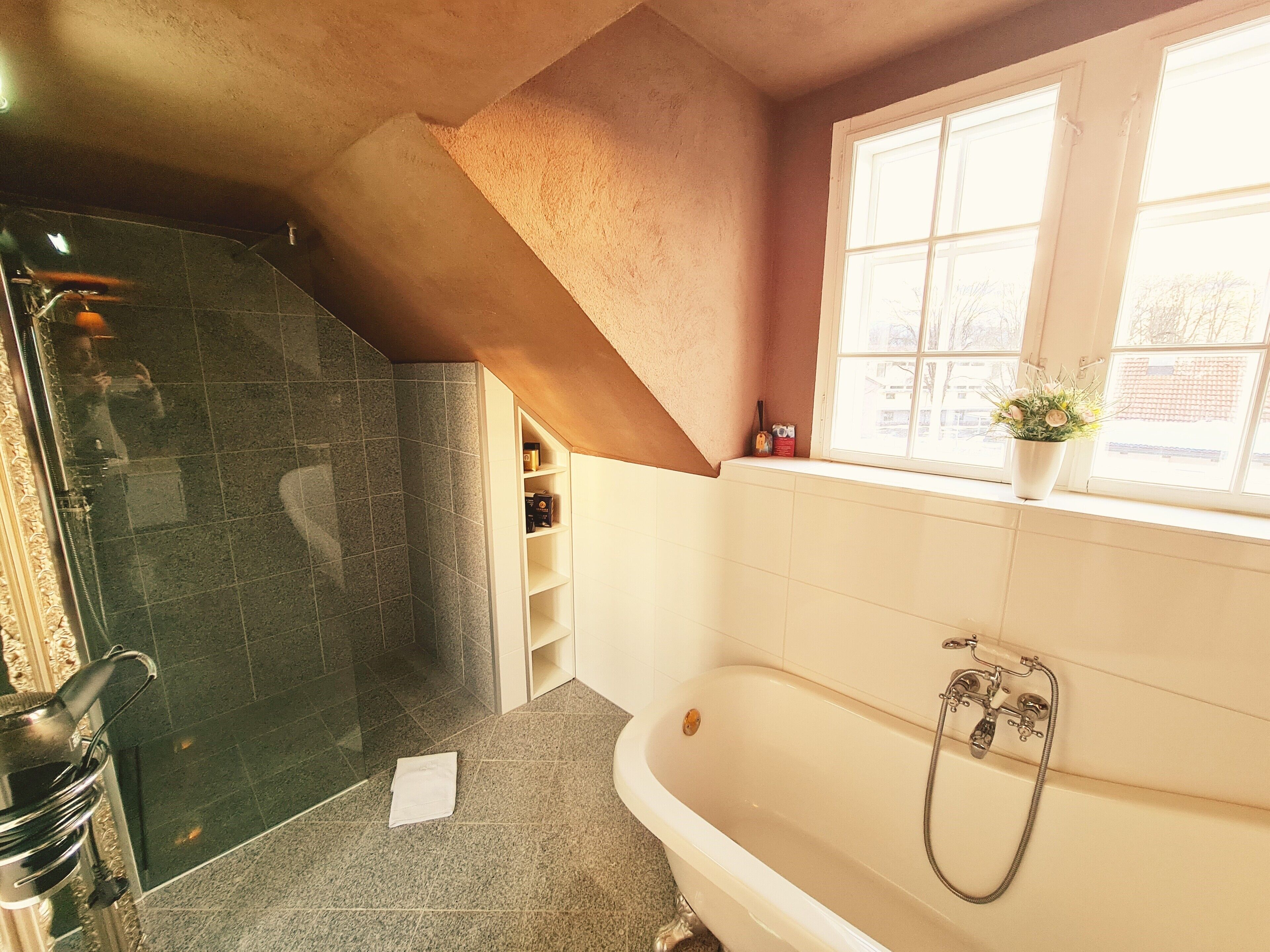 A bathroom with a bathtub, a shower, and a window with a view.