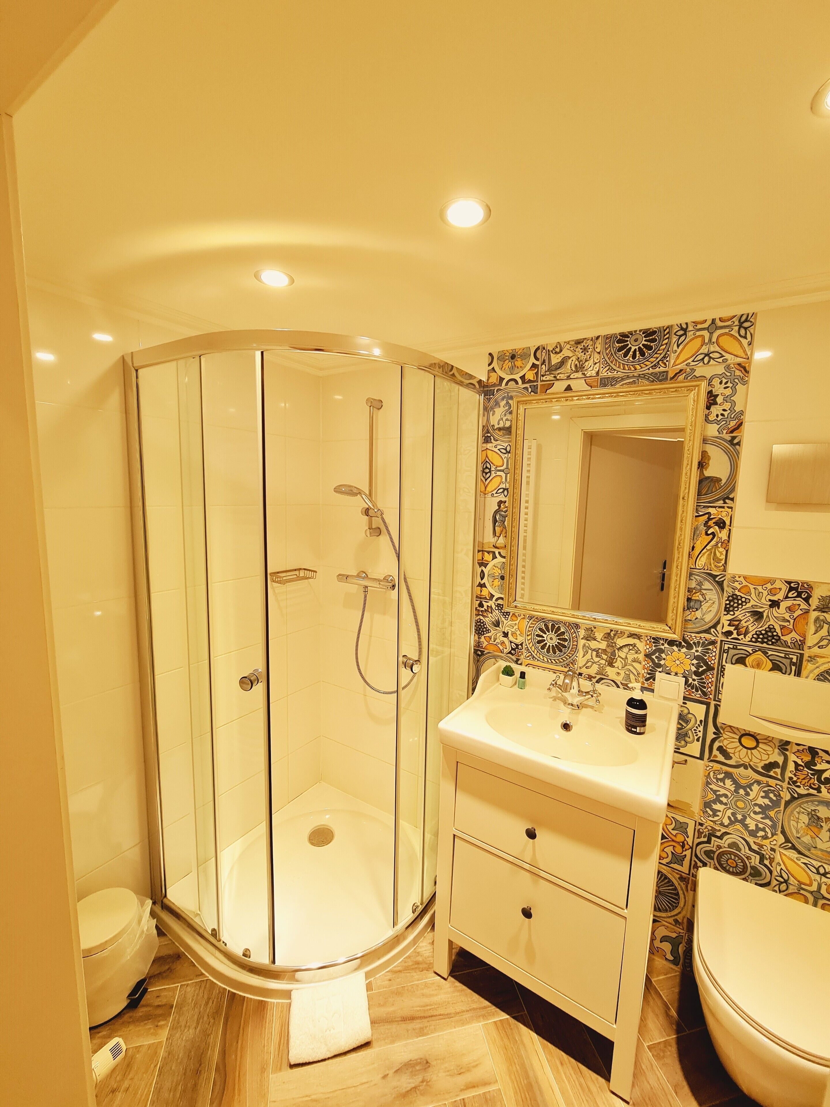 Un baño con ducha de vidrio, lavabo con espejo e inodoro.