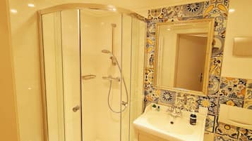 Un baño con ducha de vidrio, lavabo con espejo e inodoro.