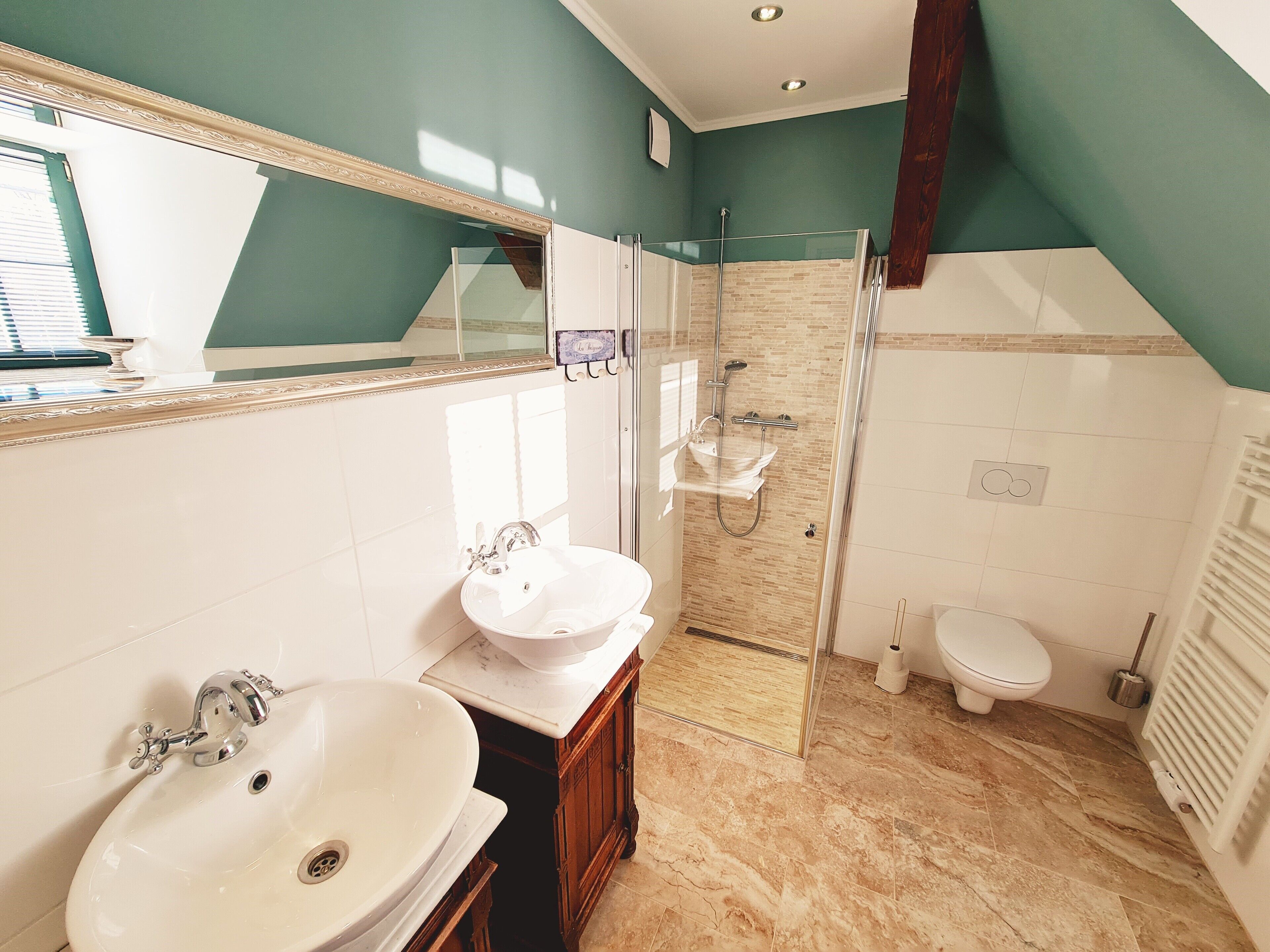 Un baño moderno con un espejo grande, dos lavamanos, una ducha y un inodoro.
