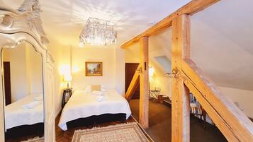 A bedroom with two beds, a chandelier, a painting, and a wooden staircase.