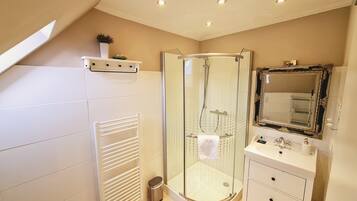 A modern bathroom with a glass-enclosed shower, a vanity with a mirror, and a towel rack.