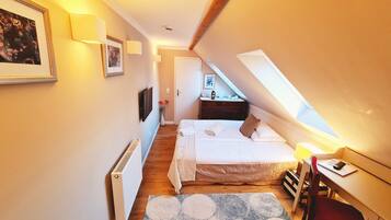 A bedroom with a bed, a desk, a chair, a radiator, and a window.