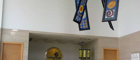 Un espace d’accueil d’hôtel au design moderne, comprenant un comptoir d’accueil, un logo circulaire sur le mur et deux portes en bois.